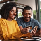 Man and woman use a cell phone and credit card to pay a bill. 